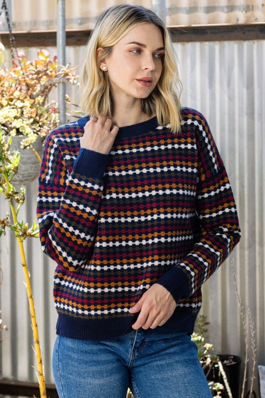 Model wearing a Staccato navy honeycomb knit sweater with burgundy, mustard, and cream stripes.
