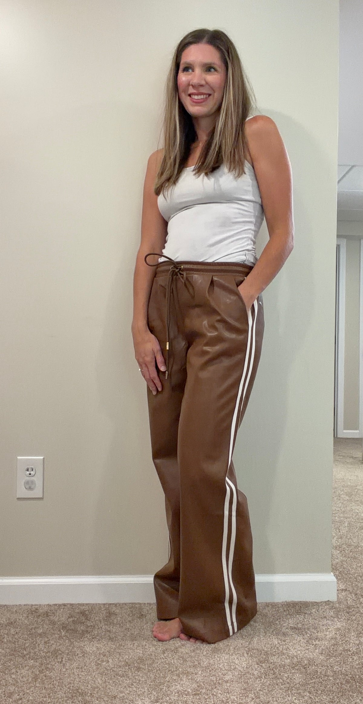 Chocolate brown faux leather wide-leg pants with a drawstring waist, styled with a white tank.