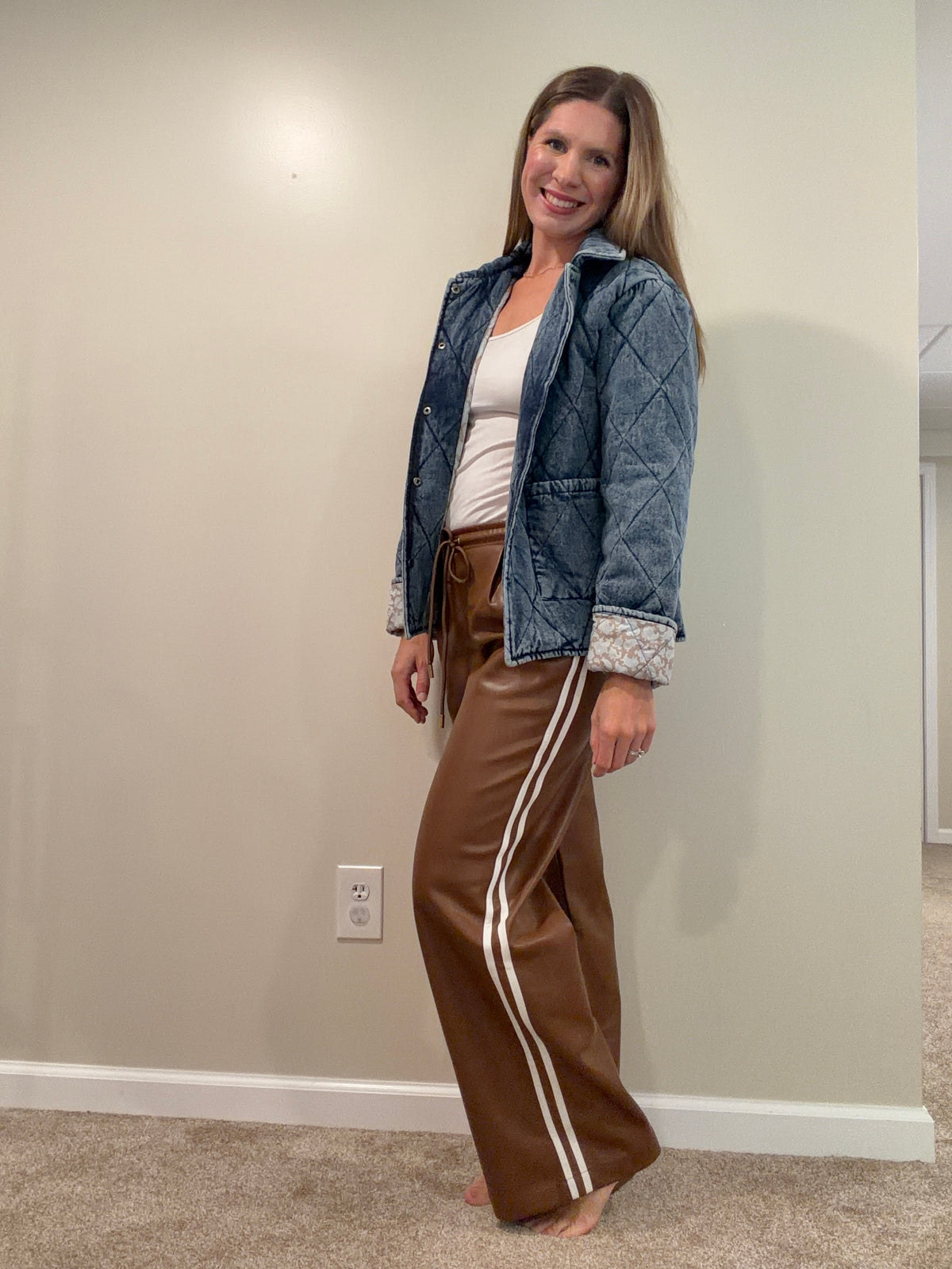 Chocolate brown faux leather wide-leg pants with cream side stripes, styled with a quilted denim jacket.